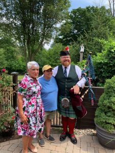 Dawn & Devon Pohl with A Bagpiper at STCGNY Summer 22 Party